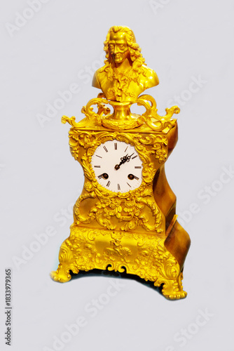 Antique mantel clock with striking golden color isolated on a light background. Items watches antiques technologies World tourism.