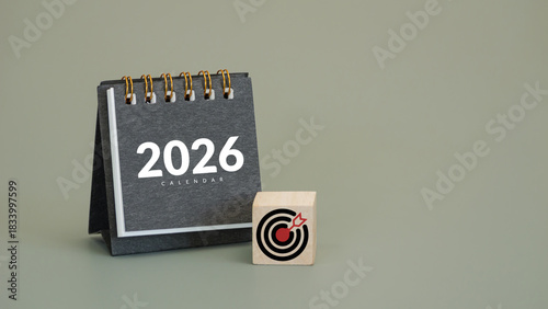 black desk calendar year 2026 with target icon on wooden cubes with copy space, symbolizing goals and planning, business strategy for new year 2026