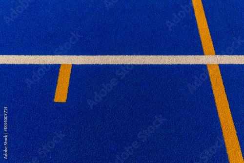Vibrant blue sports field with distinct yellow and white markings during a sunny afternoon