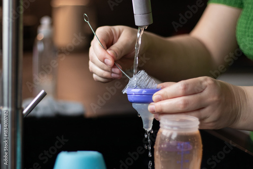 Close up of a woman cleaning a bottle and nipple for baby milk with a brush
