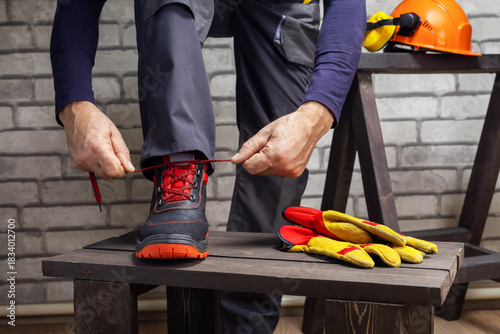  Worker putting on safety boots. Work safety protection equipment.