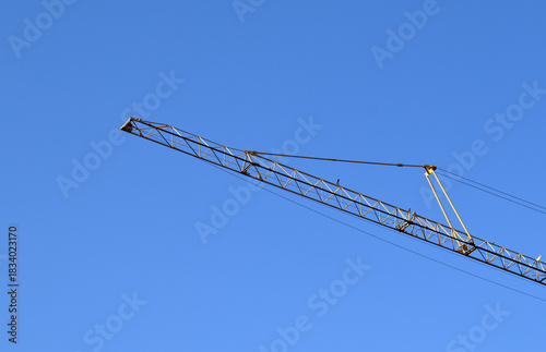 Industrial Tower Crane seen against Blue Sky 