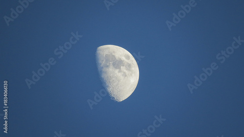 Zoom view of the moon and craters in high definition, silhouetted against the sunset sky