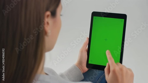 Woman holding tablet with green screen touching display
