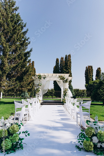 Photos Elegant outdoor wedding ceremony with decorated aisle and flower arch in a garden setting