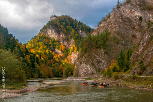 Raft with tourists floating along Dunajec gorge in Pieniny National Park., Poland at sunny autumn day. Dunajec river - popular tourist spot for boat rafting in Poland