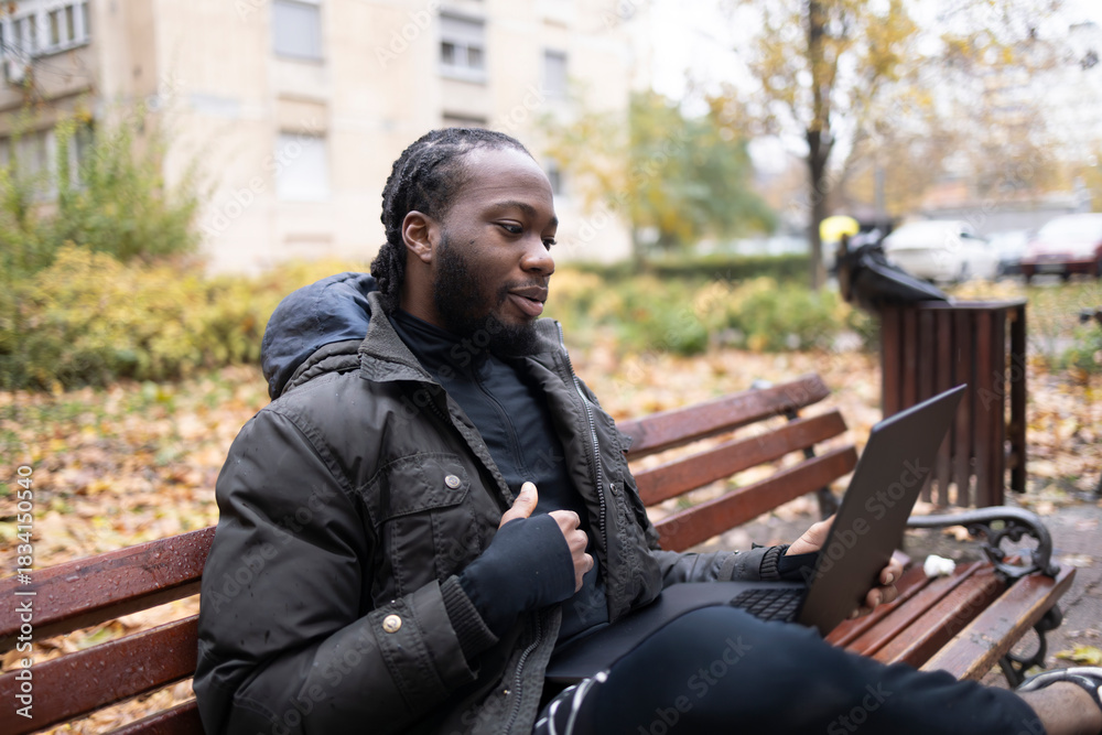 Fototapeta premium Black Young Man Using Laptop for Online Conversation in Park.