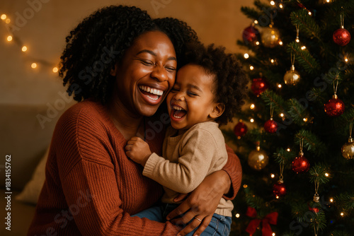 Close up afro american mother hugging daughter near christmas tree. Black family having happy time together on Christmas.
