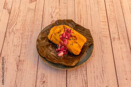Konstfotografi Colombian tamale filled with chicken, chickpeas, carrots, and capers, presented