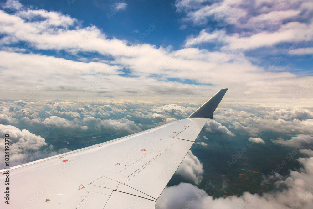 Obraz premium Flight view showing airplane wing above fluffy clouds blue sky during travel