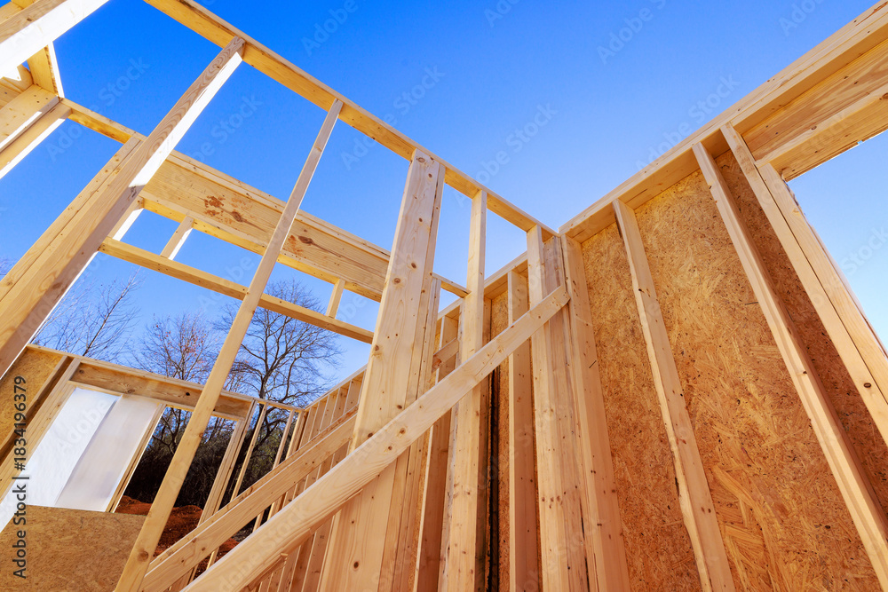 Obraz premium Sunlight shines on wooden framing beams of house under construction in quiet location