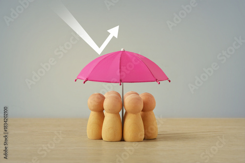 Group of wooden pawns under pink umbrella - Concept of insurance, woman and social protection