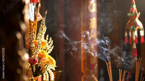Incense burning with smoke near floral offerings in a temple for culture and religion.