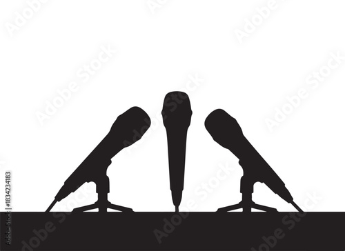  Three microphones on stands in silhouette against a white background at a press conference