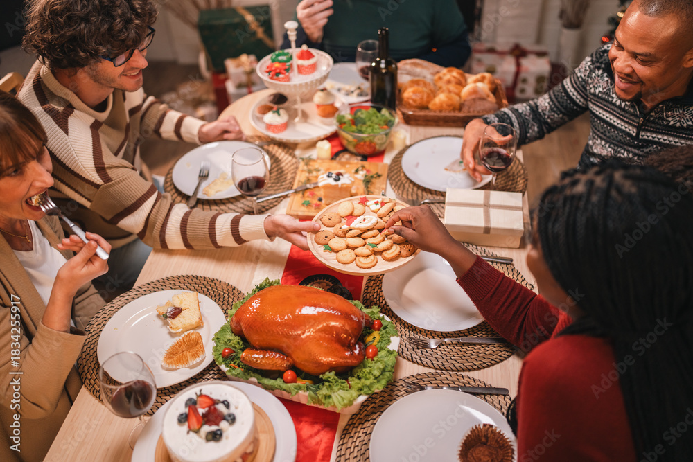Fototapeta premium Joyful holiday gathering with friends sharing festive cookies, enjoying roast turkey, and sipping red wine in a warm atmosphere filled with laughter, desserts, and seasonal decorations