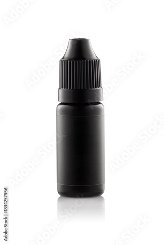 A black bottle sits on a reflective surface in a studio. The bottle has a small spout and a screw cap. The background is light, highlighting the bottle's color and shape.