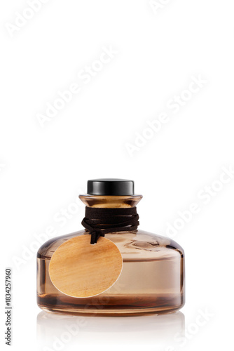 A bottle of perfume sits on a plain white background. The bottle is round with a black cap and has a wooden tag tied around its neck.