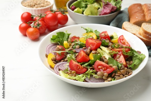 Delicious salad with lentils and vegetables served on white table, closeup
