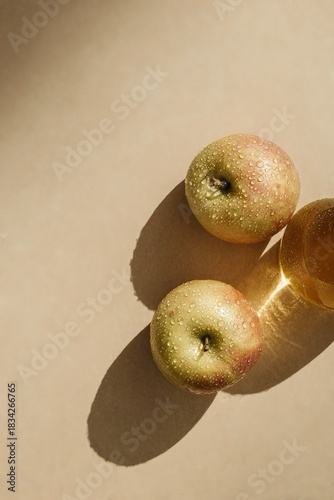 Due mele appoggiate su una superficie. Le loro ombre si proiettano sulla superficie sottostante, indicando una fonte luminosa da sopra.