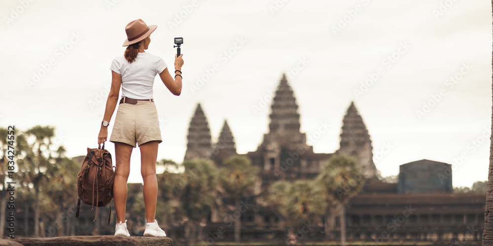 Naklejka premium Angkor Wat Vlogger: Female Traveler Filming Iconic Temple, Cambodia