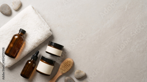 Natural beauty care products, essential oil, body cream, towel, massage brush, and stones. Spa treatment and wellness concept, top view.