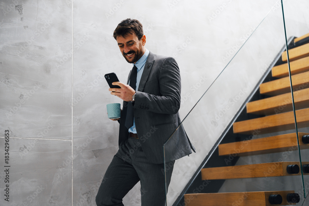 © Novak - Commuter on Stairs Checking Phone and Holding Coffee Cup