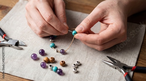 Hands of a woman crafting a beautiful beaded necklace with colorful stones and tools on a soft fabric surface, showcasing the art of DIY jewelry making