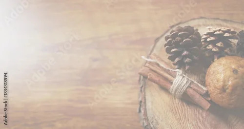 Fototapeta samoprzylepna Showing rustic wood slice on right table with cones, twine-tied cinnamon stick, cookie, copy space