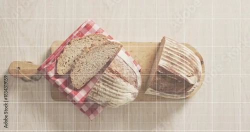 Fototapeta samoprzylepna Showing two rustic sourdough loaves resting on light wood table, with cutting boards, gingham cloth