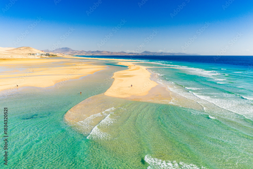Fototapeta premium Playa de Sotavento is a famous beach on the southeastern coast of Fuerteventura, known for its long stretches of golden sand, turquoise water, and consistent winds