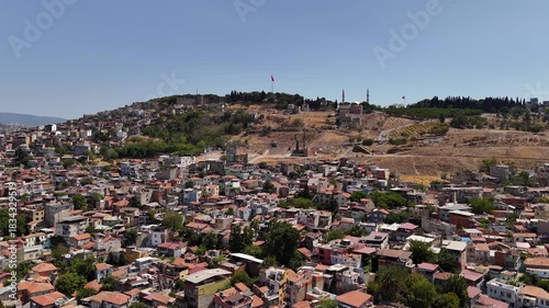 Panoramic view of the residential districts of Izmir with hills, roads and Turkish flag on the hilltop on a sunny day in Turkey. Urban cityscape and Mediterranean atmosphere.