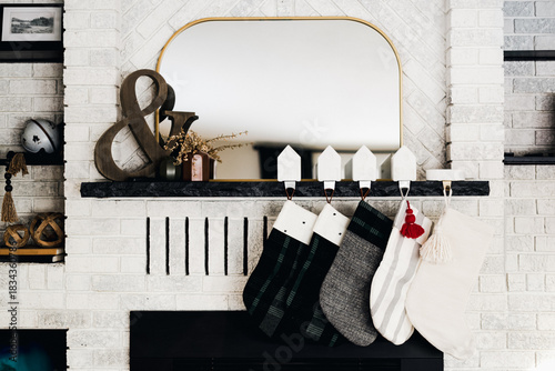 Modern Christmas Stockings on White Brick Fireplace with Mirror and Holiday Decor