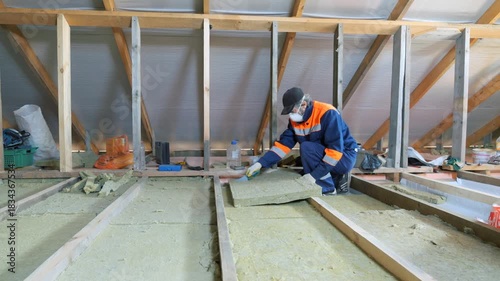 Insulation of a frame house with mineral wool. Cutting, fitting, laying insulation. Construction works.