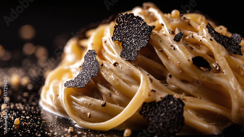 Delicate fettuccine pasta, enveloped in a rich, creamy sauce, adorned with savory truffle shavings for an exquisite culinary delight.
