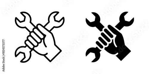 A hand holds crossed wrenches, symbolizing repair, mechanics, and construction work.