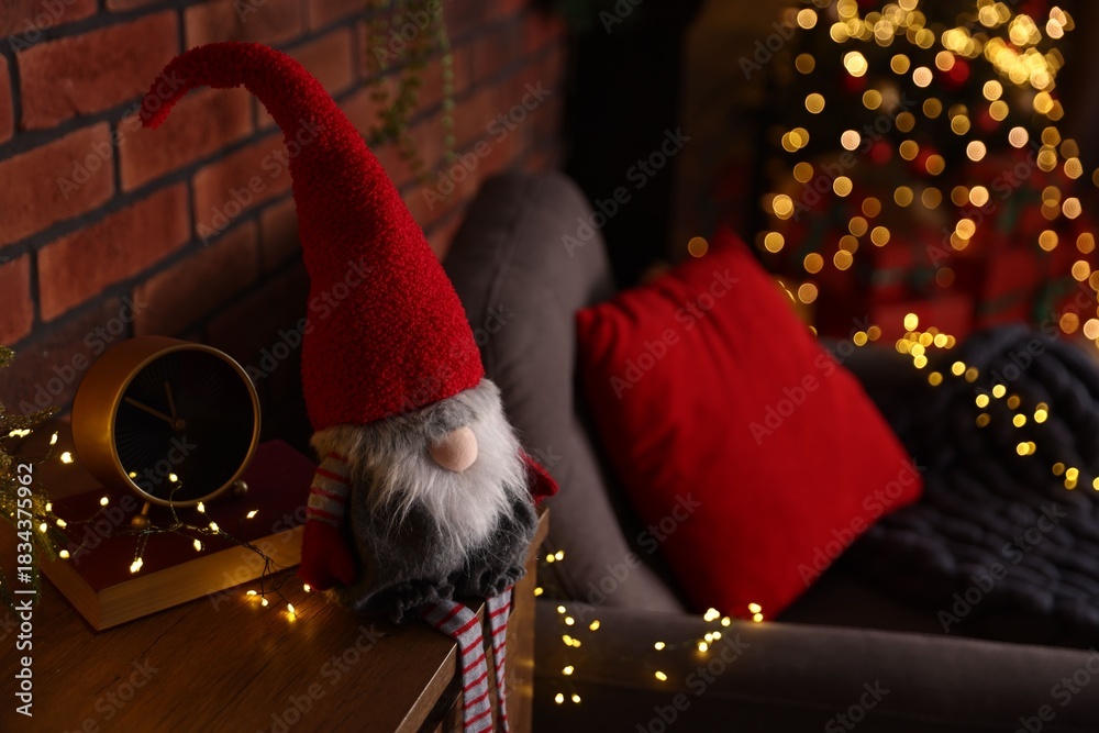 Obraz premium Funny Christmas gnome on cabinet in decorated room, closeup. Space for text