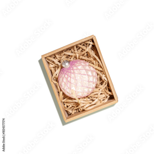 Isolated Pink Glass Christmas Ornament In Eco-Friendly Packaging On Transparent Background. Concept Of Sustainable Christmas Holiday Decorations, Winter Holidays, Eco-Gift Wrapping, Conscious Living