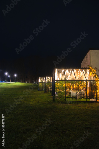 Cozy illuminated garden cabins glow warmly at night on an open lawn, creating a festive and inviting atmosphere in the dark.