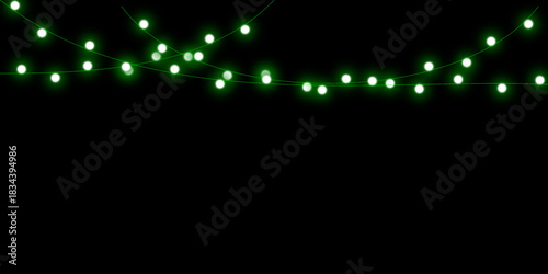 Glowing green Christmas fairy lights hanging in two delicate strings against a solid black background.
