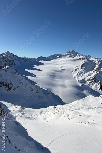 Ski resort view with cable cars moving over a snowy slope. A skier descends in the foreground. Foggy mountain backdrop adds a calm, wintry mood.