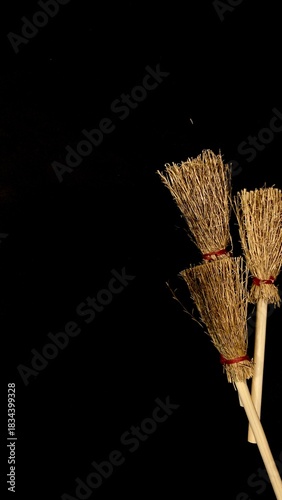 Mini witch brooms on black background, occult props, mystical composition, esoteric tools for magic and rituals