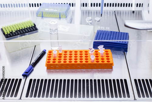 A scientist's workstation in a laboratory. The workstation contains a rack of test tubes, a solution in a cylinder, and automatic pipette tips.