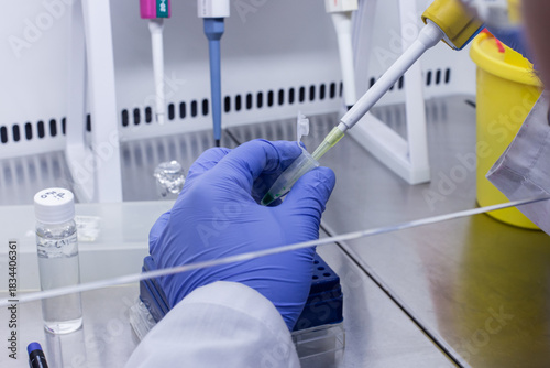 A scientist adds the sample to be tested to a small test tube using a thin tip and an automatic dispenser.