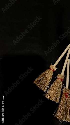 Mini witch brooms on black background, occult props, mystical composition, esoteric tools for magic and rituals