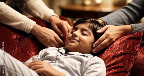 Loving father gently soothes young son to sleep with tender head massage on cozy red sofa, bedtime bonding moment, peaceful family time