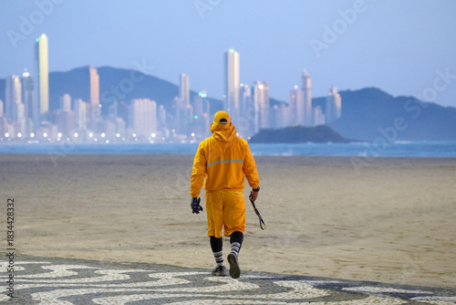 Foto Environmental worker in protective suit walking on beach with city skyline