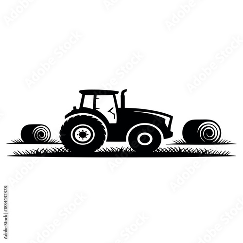 Silhouette of a tractor with hay bales in a field