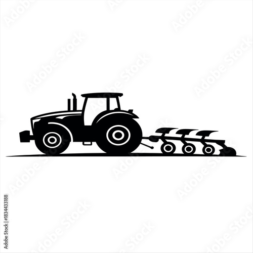 Silhouette of a tractor pulling a plow in a field