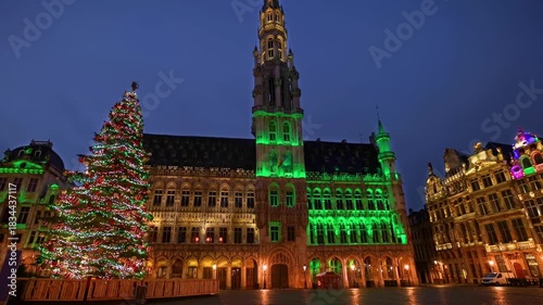 The festive decorated Grand Place in Brussels, Belgium, with a Christmas tree in front of the City Hall during dawn without people