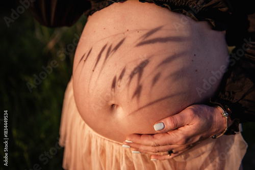 Pregnant woman cradling belly in nature setting